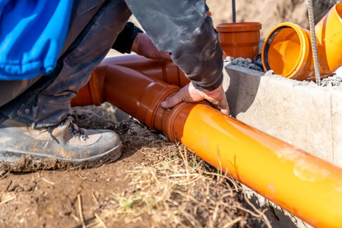 Laying an effluent pipe by hand during a septic installation
